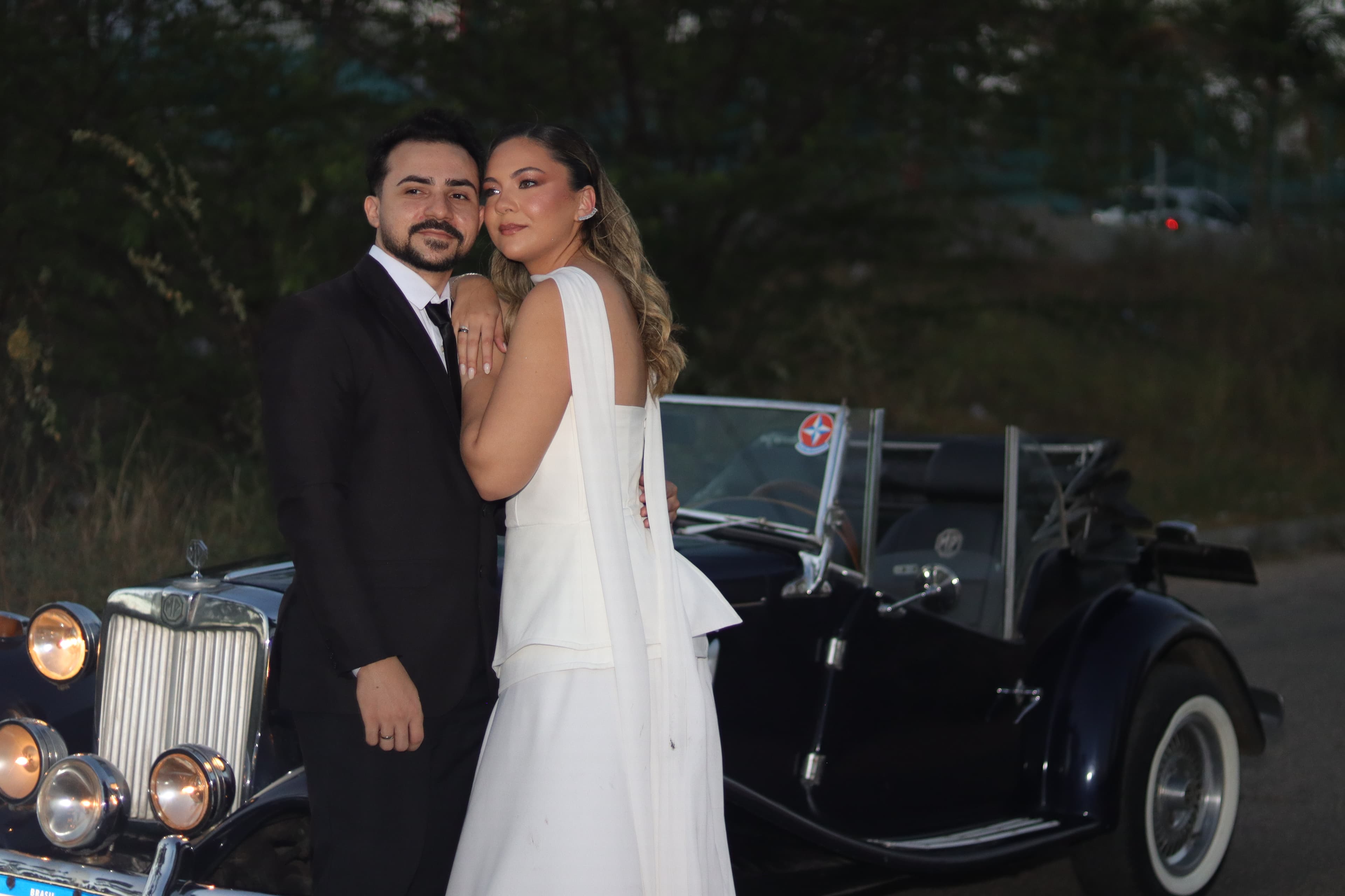 Gabriellly e Rellyson abraçados após por do sol, no final de luz do dia, com foto tirada com flash. Os dois olham para o horizonte 